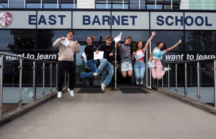 Students jumping in the air outside the front of the East Barnet School building.
