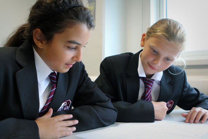 Two students studying the East Barnet School curriculum at a table