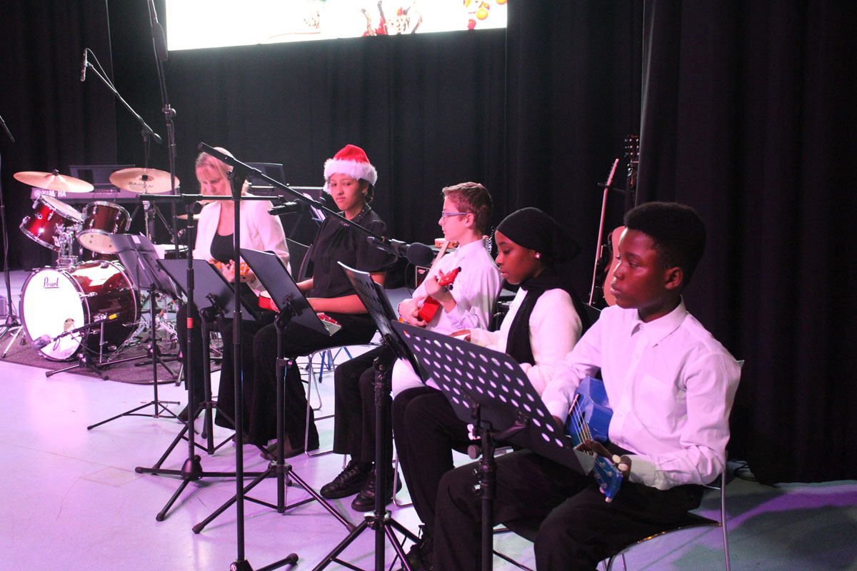 A group of students sitting down playing ukulele at the East Barnet School Winter Concert.