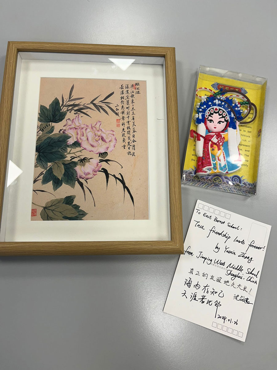 A framed image, doll and postcard gifted to east barnet school from chinese visitors
