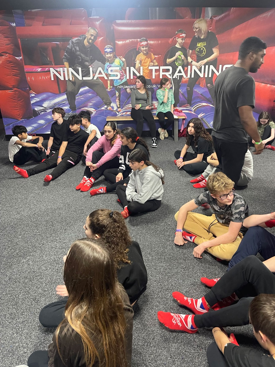 students sitting around learning more about ninja warrior uk courses