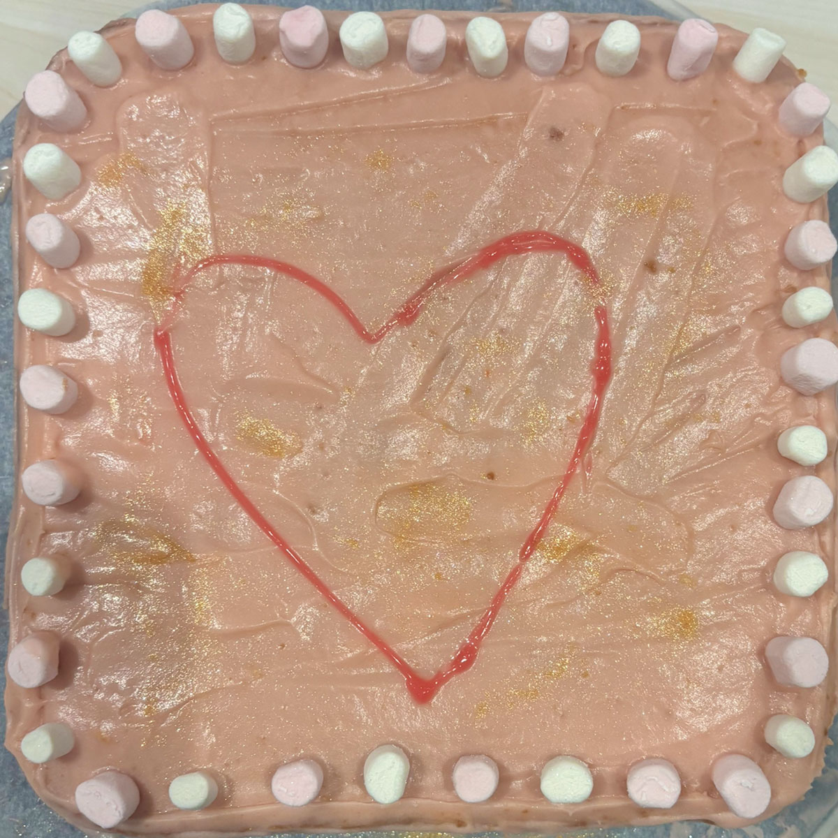 a square cake with brown and gold icing and a red heart in the middle for the ebs cake competition