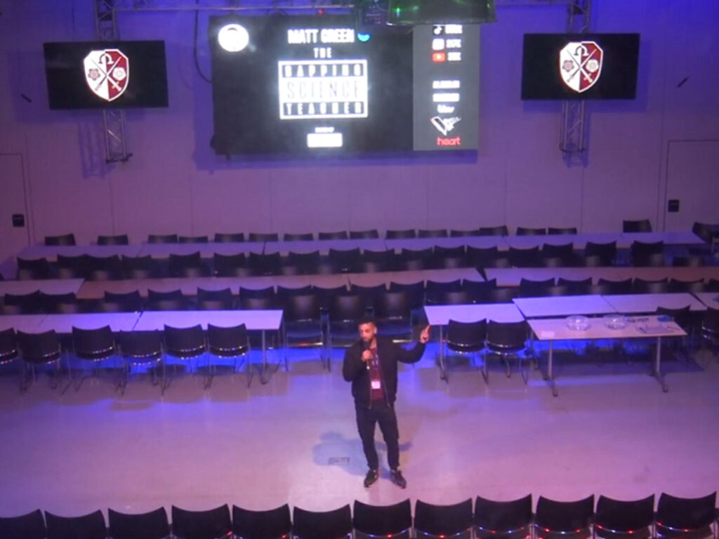 Matt Green in the East Barnet School Auditorium with The Rapping Teacher written on the screen behind