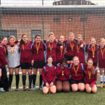 year 8 girls standing for a team photo in front of the football goal after winning the middlesex cup