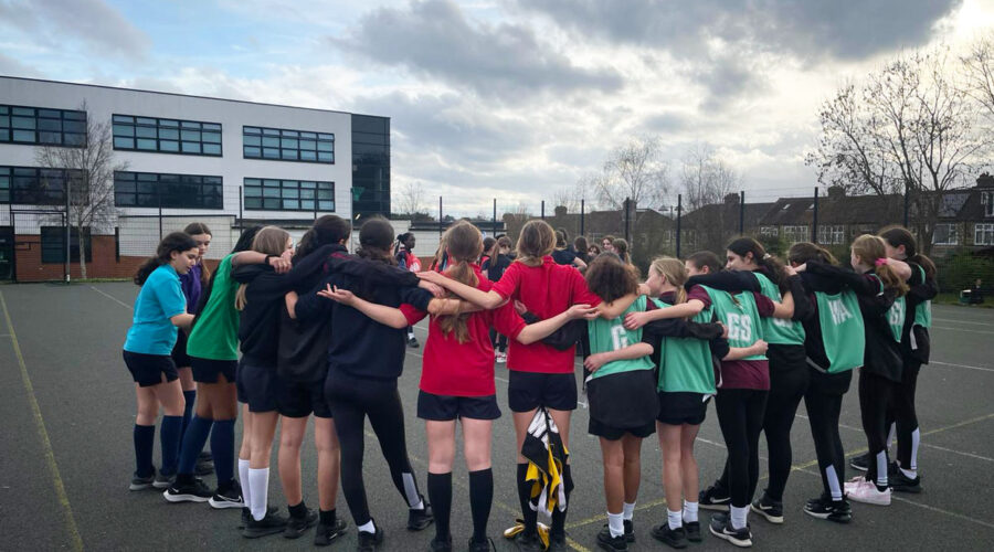 year 8 girls netball team in a huddle on the court