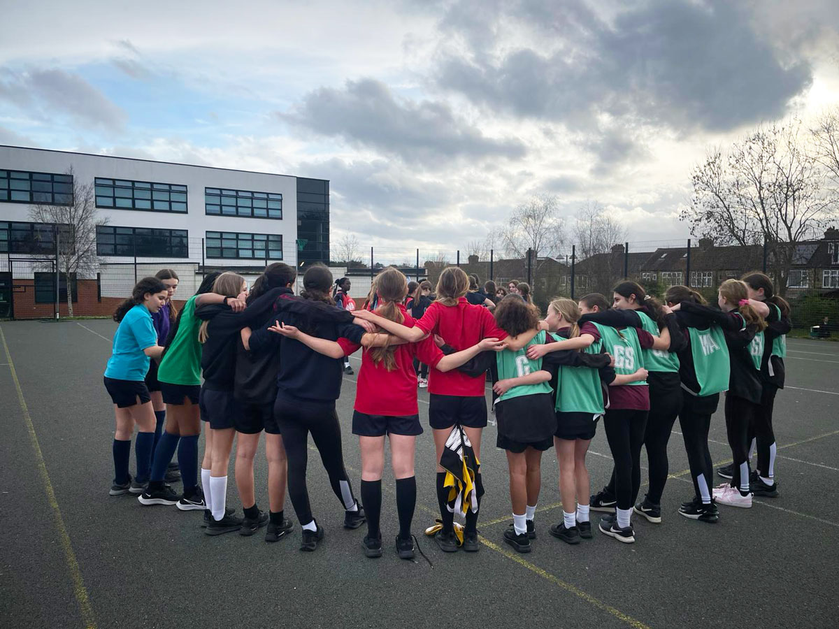 year 8 girls netball team in a huddle on the court